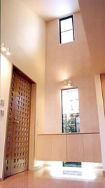 玄関ホール:広くて天井が高く、贅沢な空間になりました。<br>正面の収納棚下の照明がアクセントになっています。<br>ホール左手のリビングルームに続く格子の木製ドアは、既製品ではなく、製作(オーダーメード)したものです。